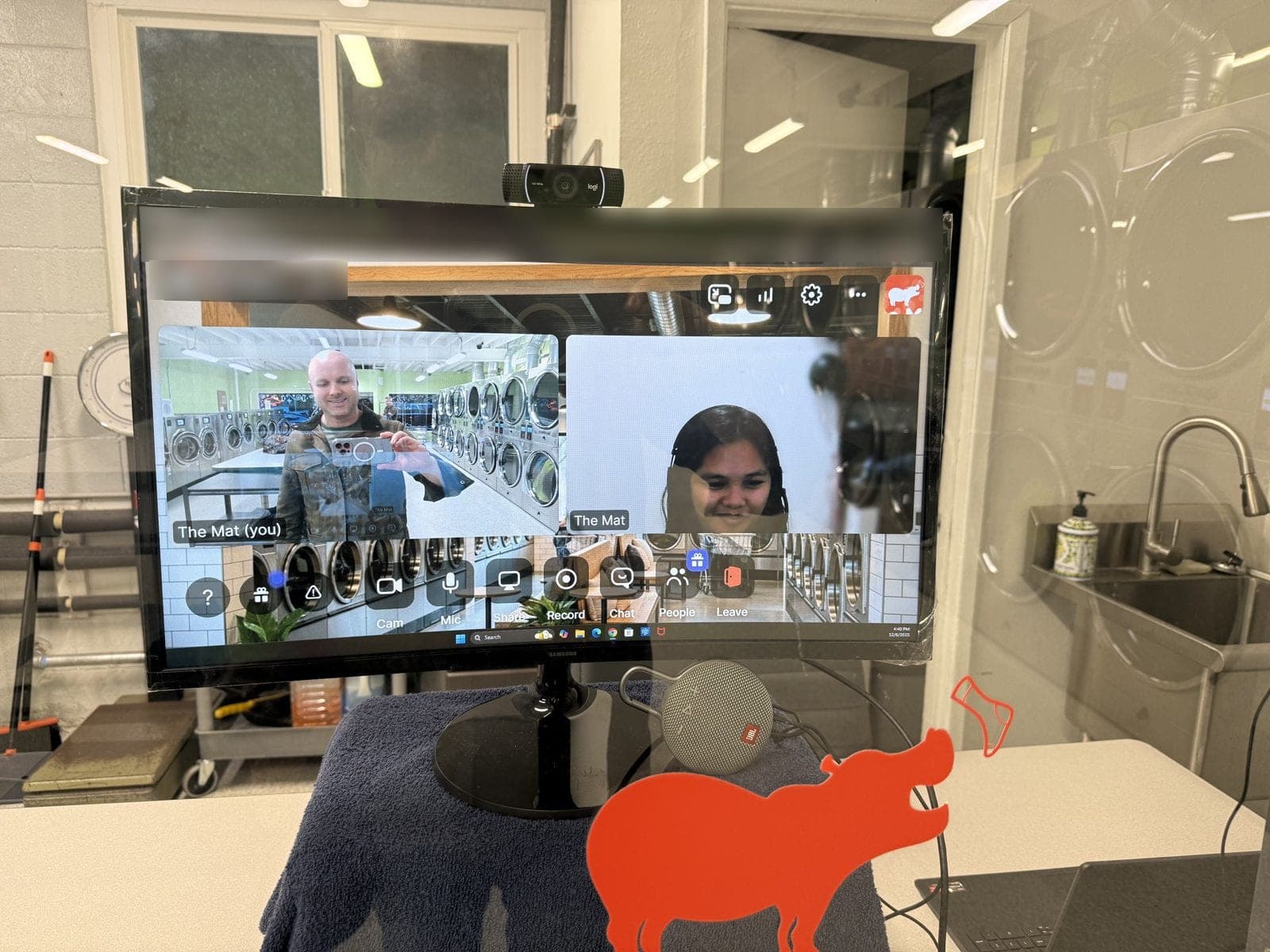 The Virtual Attendant screen inside The Mat, showing a live video call with a member of staff, next to an orange hippo cut-out